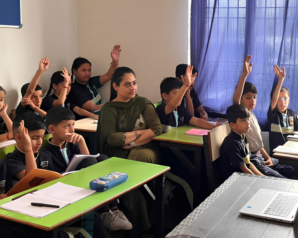 Testing the Adaptive Skills Framework curriculum with joyful students in a Dharamshala classroom while a teacher observes.