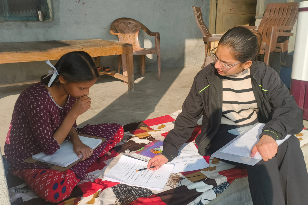 EIF field associate gathering frontline educational data by conducting a rural learning assessment with a young girl in Gopalpur village.