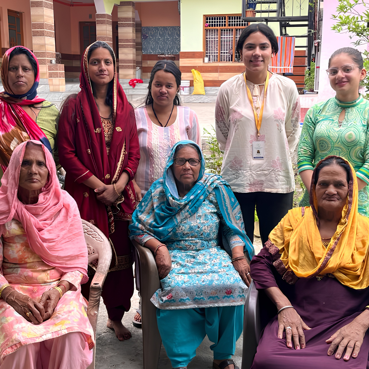 EIF President and field associate standing with a multi-generational group of female caregivers in Sukkar village following a grassroots digital literacy session.