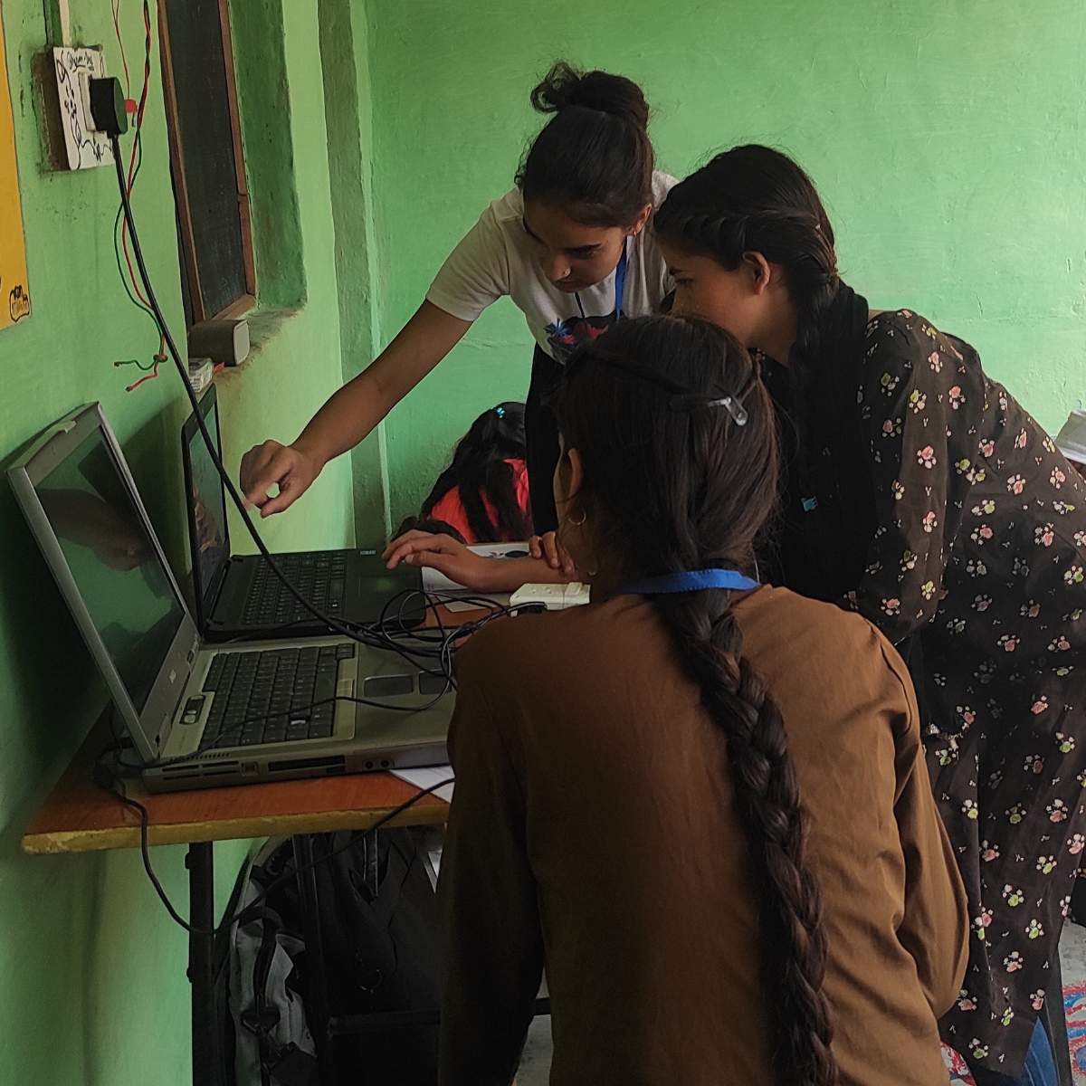 A local EIF female community leader teaching digital skills and computer literacy to young rural girls at the Rakkar Learning Hub.